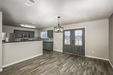 Kitchen with decorative light fixtures, stainless steel appliances, dark wood-type flooring, and gray cabinetry