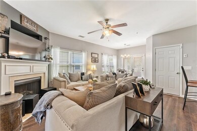 Living room with ceiling fan, dark wood-type flooring, a premium fireplace, and a chandelier