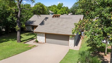 View of front of property featuring stone siding, a shingled roof, a garage, and a front lawn