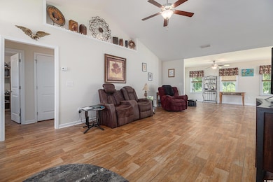 Living area featuring ceiling fan, light wood-style flooring, and high vaulted ceiling