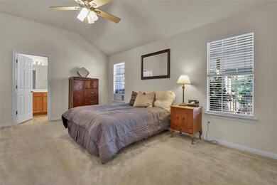Bedroom with light carpet, lofted ceiling, ensuite bathroom, and ceiling fan