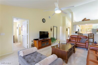 Carpeted living room with ceiling fan and high vau