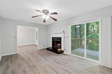 featuring ceiling fan, wood finished floors, and a lit fireplace