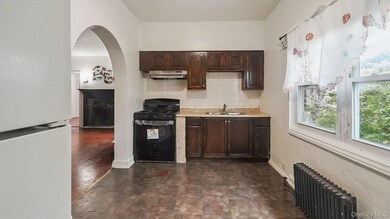 Kitchen with dark brown cabinets, freestanding refrigerator, light countertops, and black range with gas stovetop