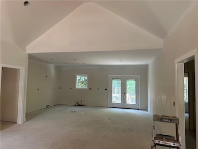 Unfurnished living room with french doors and high vaulted ceiling