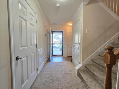 Foyer entrance with crown molding, a textured ceiling, stairs, carpet flooring, and a decorative wall