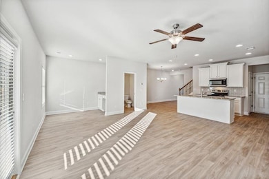 Kitchen featuring tasteful backsplash, stainless steel appliances, a center island with sink, light hardwood / wood-style floors, and white cabinetry