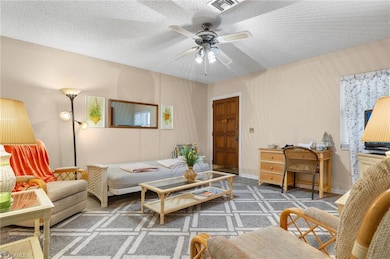 Living room featuring ceiling fan, dark carpet, an