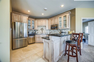 Kitchen featuring stainless steel appliances, light brown cabinetry, backsplash, kitchen peninsula, and a breakfast bar area