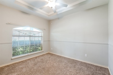 Unfurnished room with a tray ceiling, carpet, crown molding, and ceiling fan