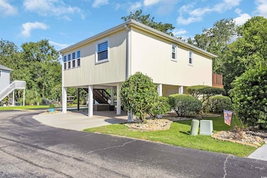 View of front of house with a carport, stairs, and concrete driveway