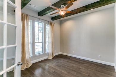 Office off of the entry features hardwood beams and large windows for natural light.
