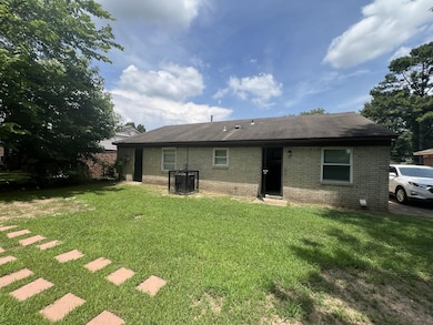 Rear view of house with brick siding, a yard, and a shingled roof