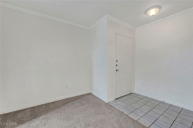Empty room featuring crown molding, baseboards, li