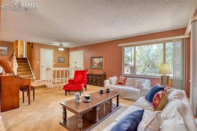 Living room featuring light carpet, stairway, a textured ceiling, and ceiling fan