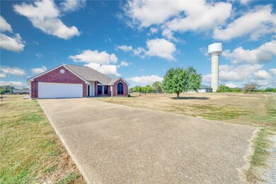 Single story home with driveway, brick siding, a front yard, and an attached garage