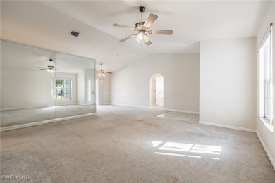 Carpeted empty room with ceiling fan and vaulted c
