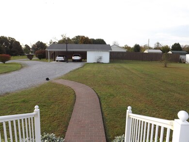 The view from the back porch shows the detached carport with large storage room.  Privacy fence in back.