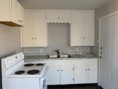 Kitchen featuring white cabinets, white range with