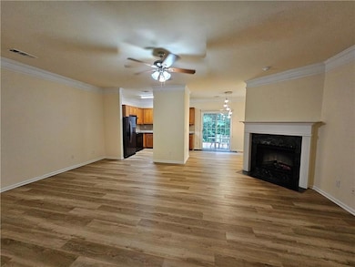 Unfurnished living room with crown molding, ceiling fan, wood finished floors, and a fireplace