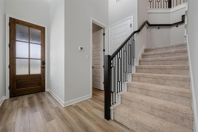 Foyer entrance featuring stairway, light wood fin