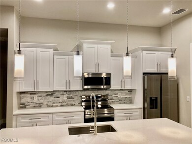 Kitchen featuring stainless steel appliances, white cabinetry, and backsplash