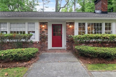 Doorway to property featuring a chimney, brick siding, and a shingled roof