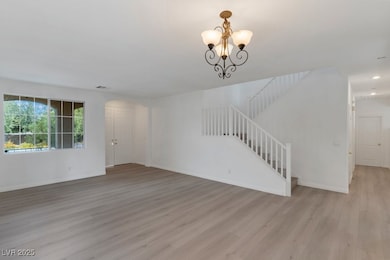 Unfurnished living room with stairs, light wood-style floors, arched walkways, and a chandelier