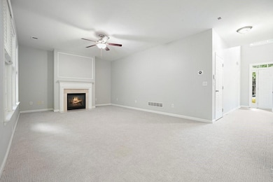 Unfurnished living room with ceiling fan, light colored carpet, and a fireplace with flush hearth