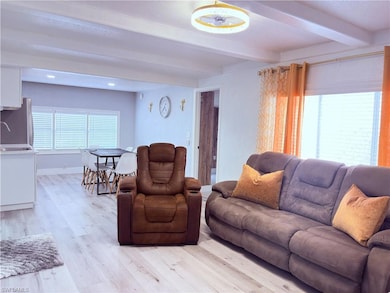 Living area with beamed ceiling, light wood-style flooring, and recessed lighting