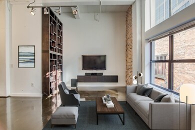 Virtual staging of the living room. Exposed brick and 15 ft. ceilings in this loft-style condo. Custom bookcase, TV and sound system included.