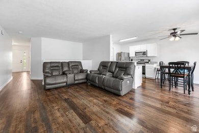 Living area featuring dark wood-type flooring and ceiling fan