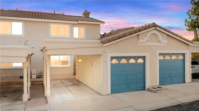 View of front facade featuring stucco siding, a tile roof, a chimney, and a garage