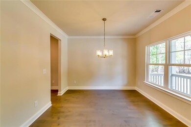 Empty room featuring ornamental molding, dark wood-style flooring, a chandelier, and baseboards