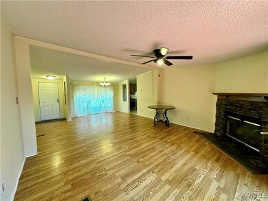 Living room featuring a textured ceiling, ceiling fan with notable chandelier, hardwood / wood-style flooring, and a fireplace