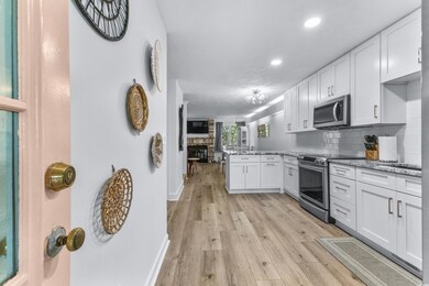Kitchen with stainless steel appliances, a peninsula, white cabinetry, light wood-type flooring, and recessed lighting