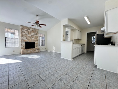 Kitchen featuring white cabinetry, light tile patterned floors, light countertops, healthy amount of natural light, and lofted ceiling