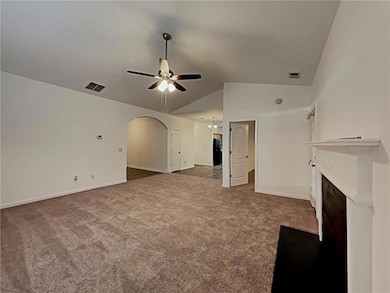 Unfurnished living room featuring a ceiling fan, lofted ceiling, carpet flooring, a fireplace, and arched walkways