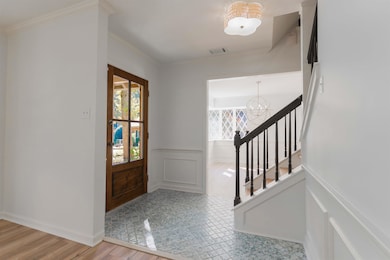 Foyer entrance with healthy amount of natural light, a wainscoted wall, a decorative wall, a chandelier, and crown molding