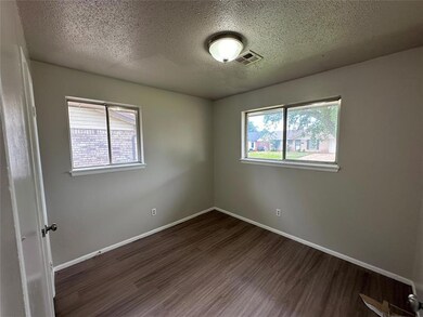 Empty room with a textured ceiling and dark wood-s