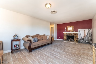 Living area with a stone fireplace, light wood-typ