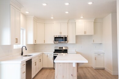 Large kitchen with quartz slab countertops, ceiling height uppers, white painted wood cabinets, dishwasher, gas range, microwave, disposal.