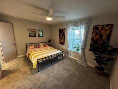 Carpeted bedroom with crown molding, a ceiling fa