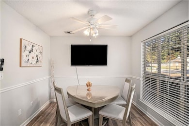 Dining area with dark wood-style flooring, a ceiling fan, and a textured ceiling