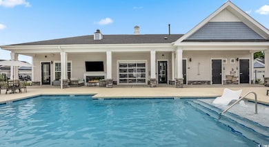 Community pool with a patio area and a lit fireplace