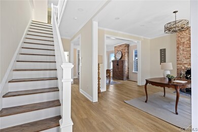 Stairs with brick wall, light hardwood floors, and