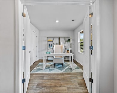 Office featuring wood finished floors, visible ven