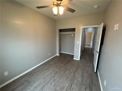 Unfurnished bedroom with dark wood-style floors, baseboards, a closet, and a ceiling fan