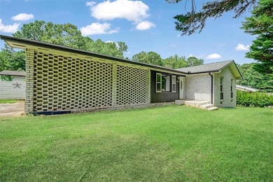 Rear view of house featuring a yard and brick siding