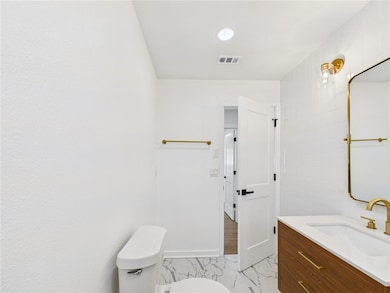 Half bathroom featuring toilet, vanity, marble fin